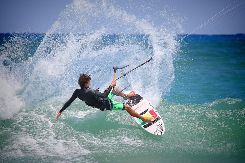 Professional kitesurfer performing aerial maneuver over turquoise water